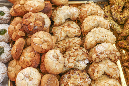 Assorted gourmet cookies including biscotti, amaretti, and sablés, arranged on a rustic serving tray.