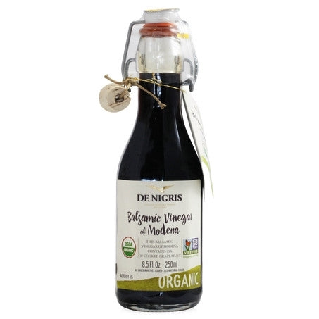Bottles of De Nigris balsamic vinegar and Italian glazes on a rustic wooden table
