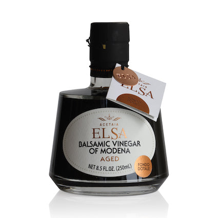 Bottles of Elsa Italian vinegar including balsamic, red wine, and white wine varieties on a rustic kitchen table