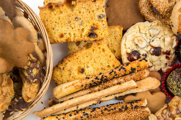 Italian grissini breadsticks arranged on a wooden board with olives and cured meats