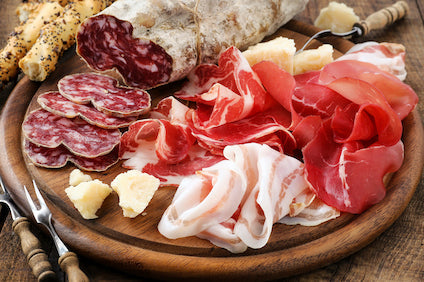Sliced Jamon Serrano on a wooden board with bread, olives, and Manchego cheese