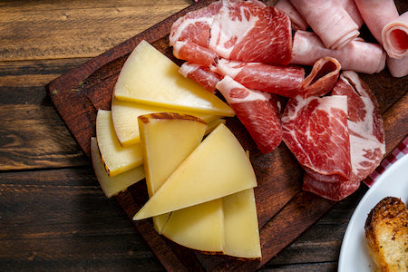 Jamon Ibérico cured ham slices on rustic board with olives and Spanish wine