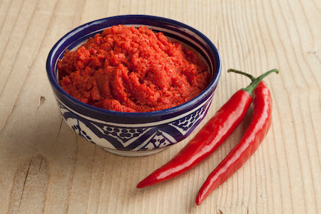 Assorted gourmet Italian peppers including Calabrian chilis, roasted red peppers, and marinated varieties in glass jars