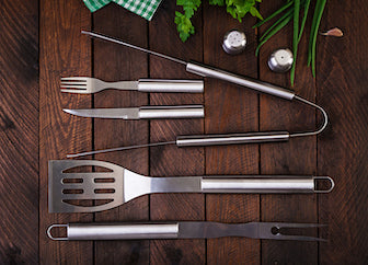 High-quality kitchen tools and gadgets including olive wood utensils, graters, and prep essentials displayed on a rustic countertop